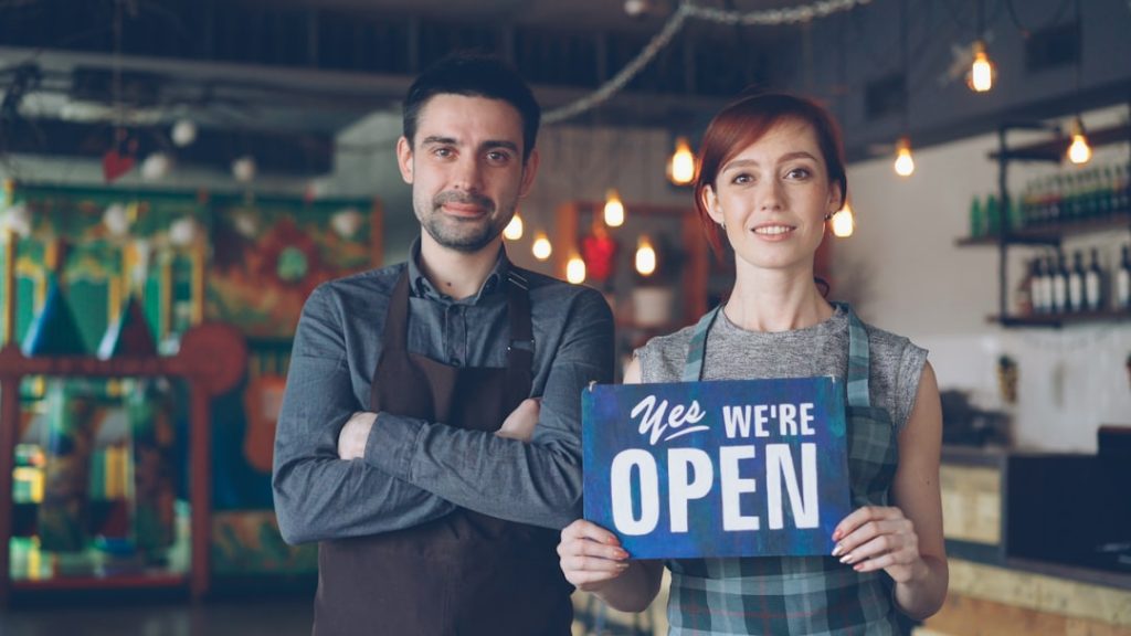 A happy couple welcomes customers: we are open.
