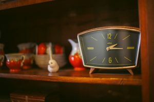 Vintage clock sits on a wooden shelf.