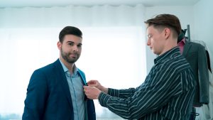 man in blue blazer standing beside man in black and white stripe dress shirt