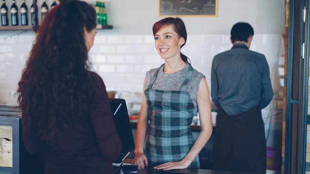 A barista smiles while talking to a customer.