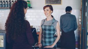 A barista smiles while talking to a customer.