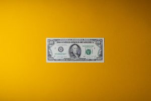 a one dollar bill sitting on top of a yellow wall