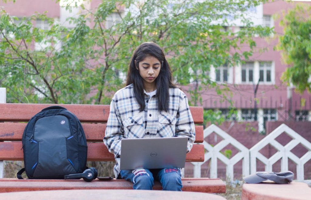 a woman sitting on a bench with a laptop