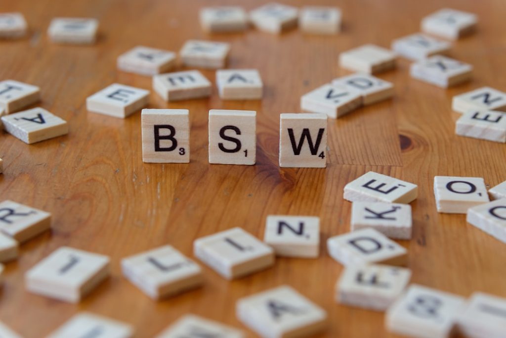 A wooden table topped with scrabble tiles spelling the word bsw
