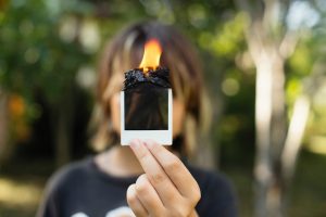 a woman holding up a cell phone with a flame on it