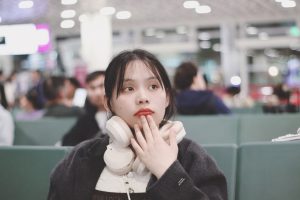 A woman looking surprised with headphones around her neck.